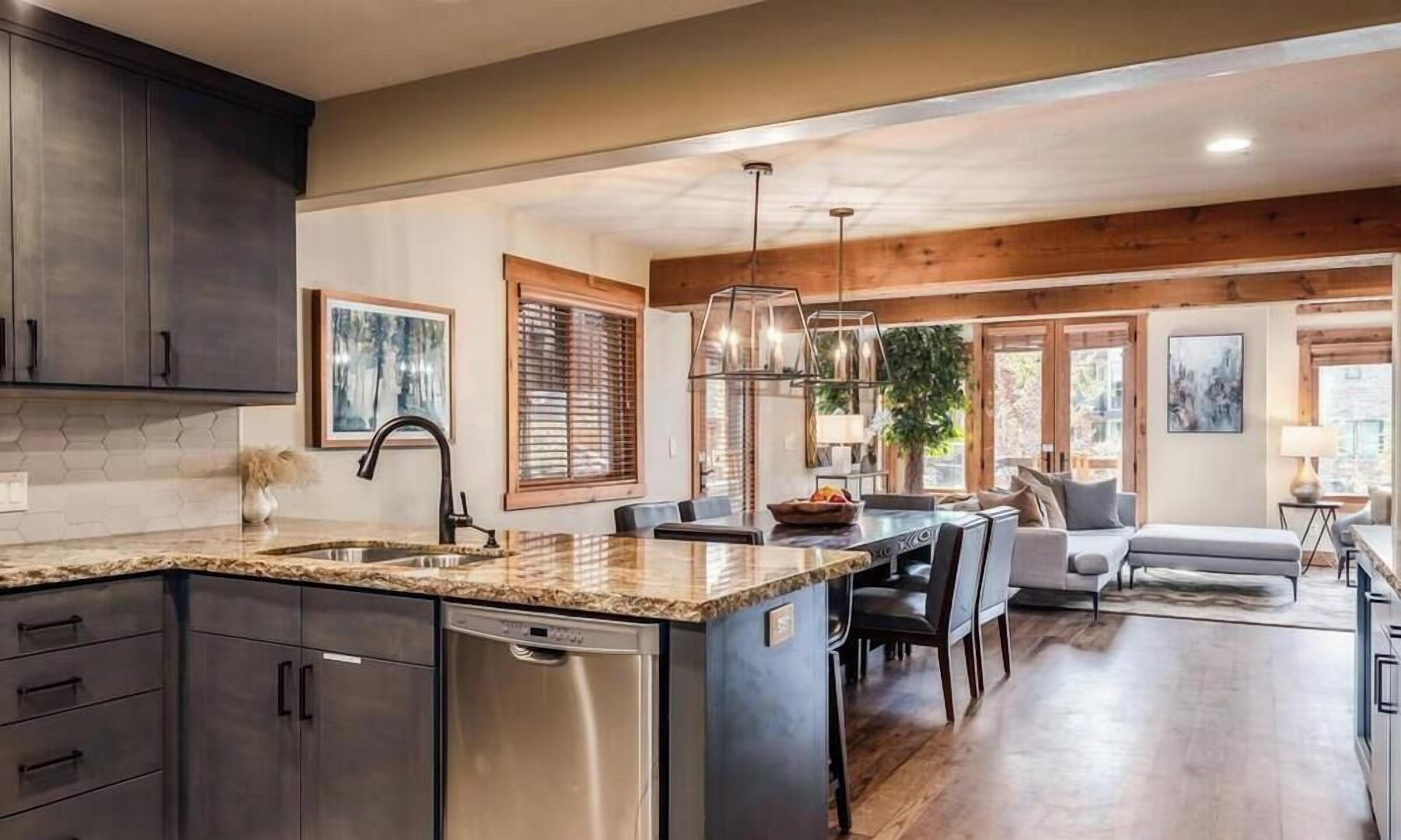 A modern kitchen with dark cabinets, a stainless steel dishwasher, and a granite countertop.