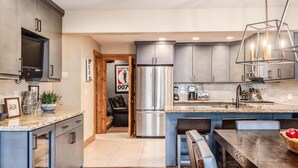 A modern kitchen with stainless steel appliances, a built-in oven, and a large island with seating.