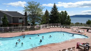A swimming pool with people in it, surrounded by lounge chairs and a view of the lake. - Harbor Village with resort amenities & unobstructed lake views (lake 3 min walk) (Garden City)