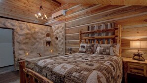 Une chambre confortable dans un chalet en rondins, avec un lit en bois, un mur en pierre et une tête de lit en bois rustique.