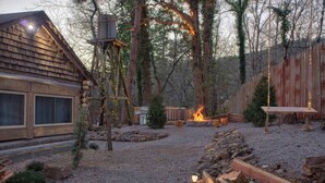Un chalet rustique doté d’un foyer en pierre, d’une terrasse en bois et d’une clôture en bois.
