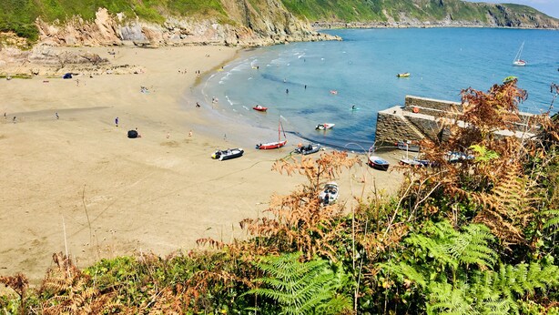 A coastal beach with a rocky cliff, a sandy shore, and a few boats. - Little Gwyn. 3 min walk to Beach! Gorgeous views out to sea. (Gorran Haven)