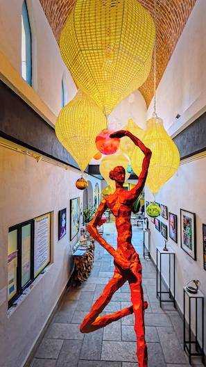 A corridor with a sculpture, framed artwork, and hanging lamps.