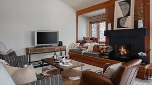 A modern living room with a fireplace, a television, and a sofa. - Outpost: Huckleberry 3124 -Wood burning fireplace! (Wilson)
