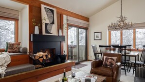 A cozy living room with a fireplace, comfortable seating, a dining area, and large windows. - Outpost: Huckleberry 3124 -Wood burning fireplace! (Wilson)