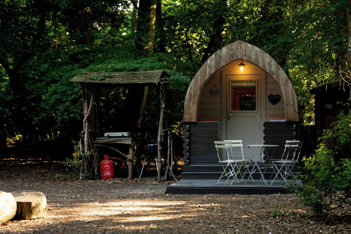 Een rustieke houten hut met een overdekte veranda, een tafel en stoelen.