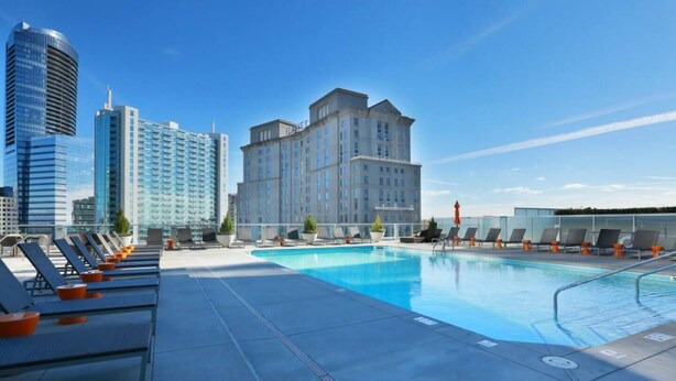 A rooftop pool with lounge chairs and a view of high-rise buildings. - Prime Downtown Atlanta Condo with Luxury Amenities (Atlanta)