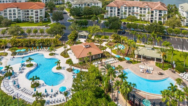 A resort with multiple buildings, a central swimming pool, and surrounding greenery. - Serene Waters at Vista Cay Resort (Orlando)