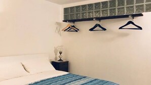 A bedroom with a bed, a nightstand, and a wall-mounted shelf with hangers. - Navel of Parma (Parma)