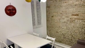 A dining area with a white table and chairs, a stone wall, and a ceiling light fixture. - Navel of Parma (Parma)