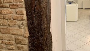 A room with a stone wall, a wooden beam, and a tiled floor. - Navel of Parma (Parma)