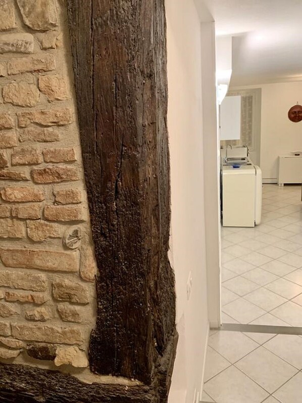A room with a stone wall, a wooden beam, and a tiled floor. - Navel of Parma (Parma)