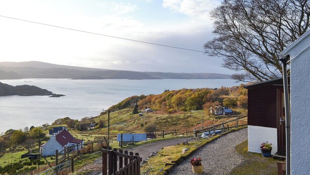 Un paisaje rural con vistas a un lago, casas y una cerca de madera.