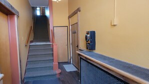 A narrow hallway with a carpeted staircase leading to a door marked "MONTANA." - Dillon Tap House Beaverhead Room (Dillon)