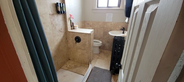 Une petite salle de bain comprenant des toilettes, un lavabo et un espace douche.