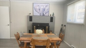 A dining room with a wooden table and chairs, a fireplace, and a large elephant painting on the wall. - Spacious 2 bedroom suite on private lot (Pemberton)