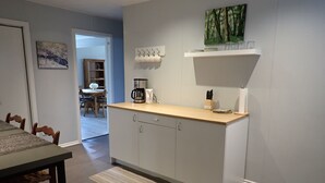 A modern kitchen with a wooden countertop, white cabinets, and a dining area with a table and chairs. - Spacious 2 bedroom suite on private lot (Pemberton)