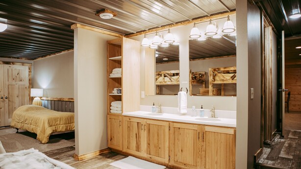 A bathroom with wooden cabinets, a large mirror, and a sink. - Experience Starbuck charm in our spacious 5-bedroom retreat (Starbuck)