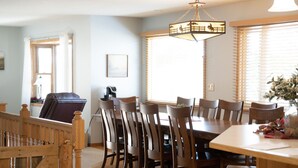 A dining area with a wooden table and chairs, a chandelier, and a window with blinds. - Experience Starbuck charm in our spacious 5-bedroom retreat (Starbuck)
