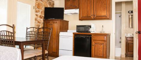 A compact kitchen with wooden cabinets, a microwave, a coffee maker, and a dishwasher.