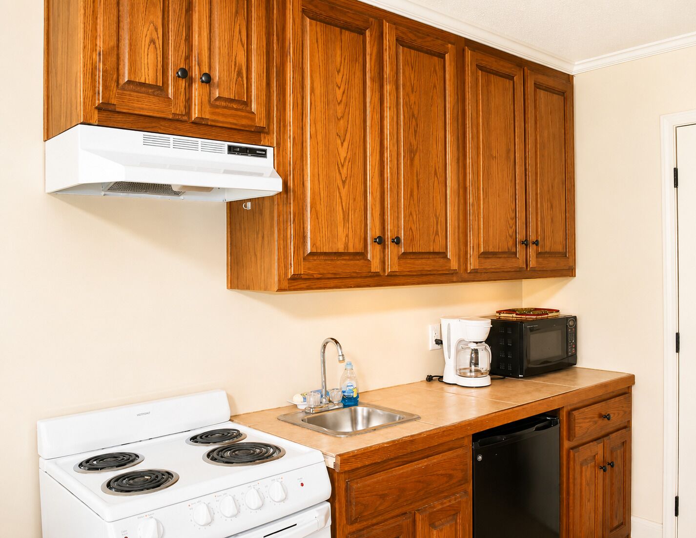Una cocina con armarios de madera, una estufa blanca, una cafetera y un microondas.