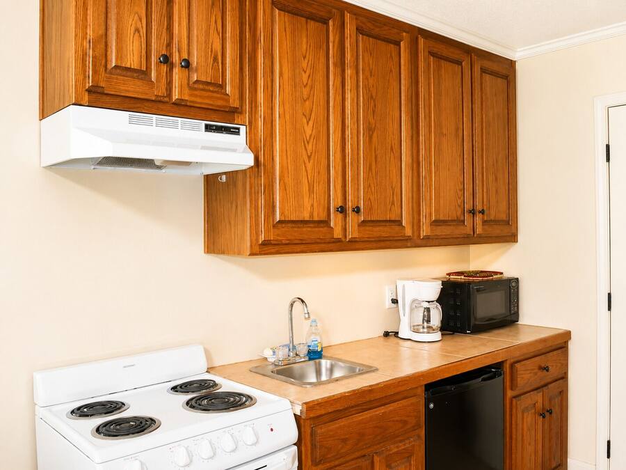 Una cocina con armarios de madera, una estufa blanca, una cafetera y un microondas.