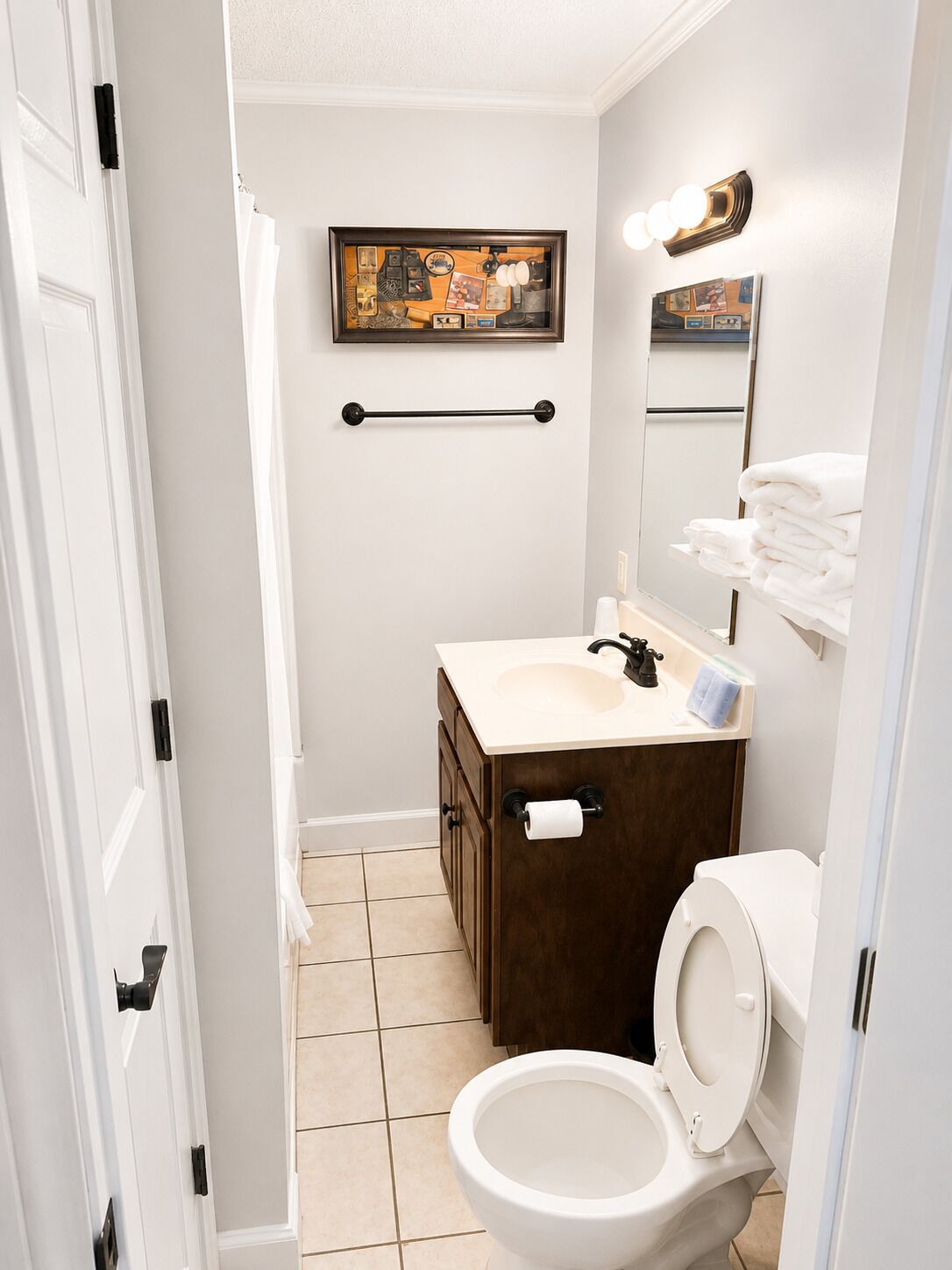 Une salle de bain équipée de toilettes, d’un lavabo, d’un porte-serviettes et d’un tableau encadré au mur.