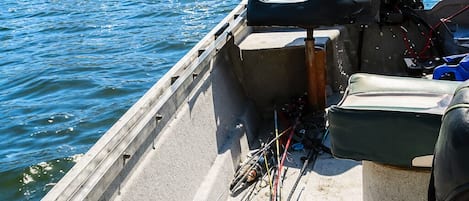 A boat with a motor, a seat, and fishing rods.