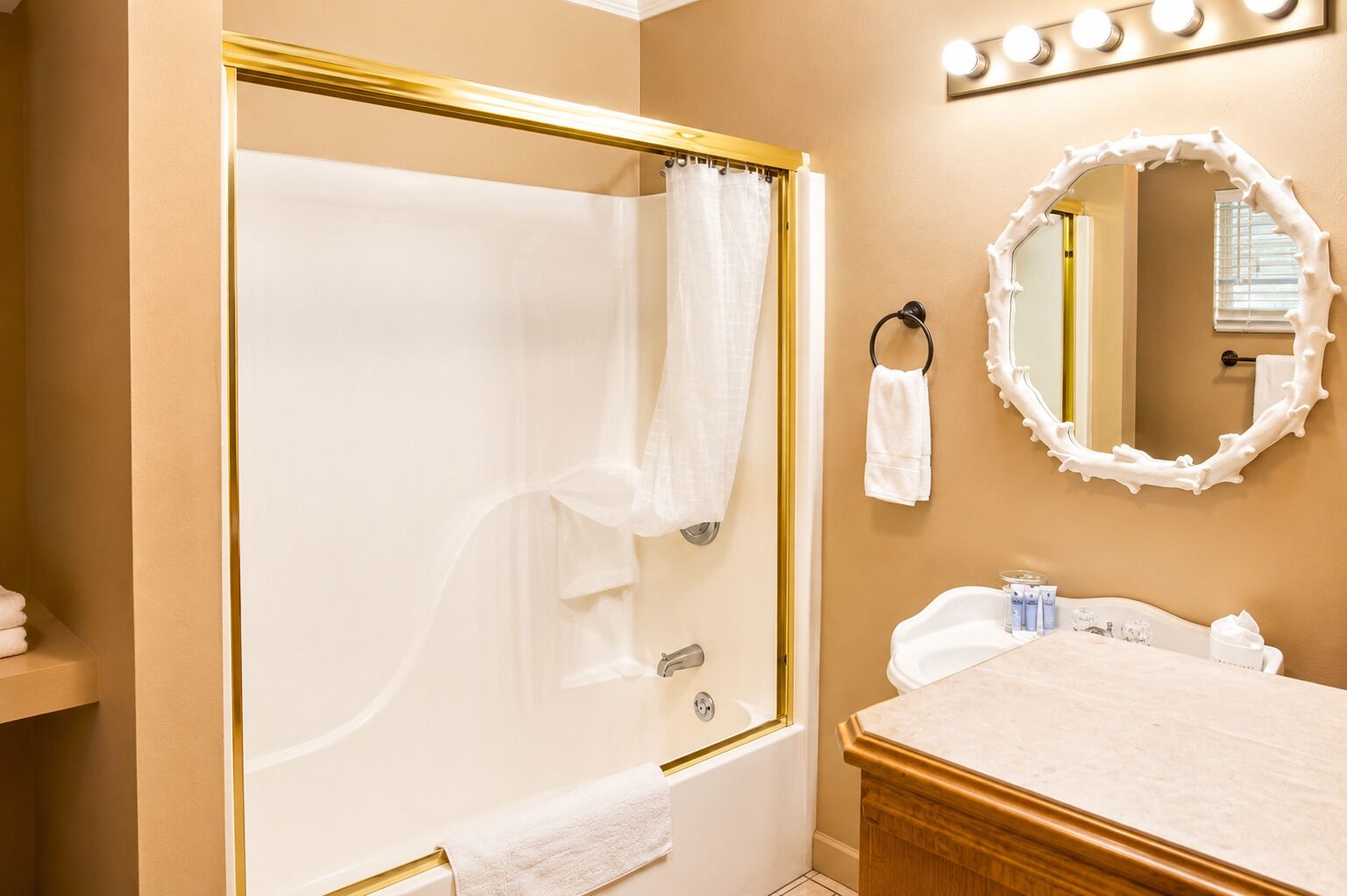 A bathroom with a bathtub, a vanity with a mirror, and a towel rack.