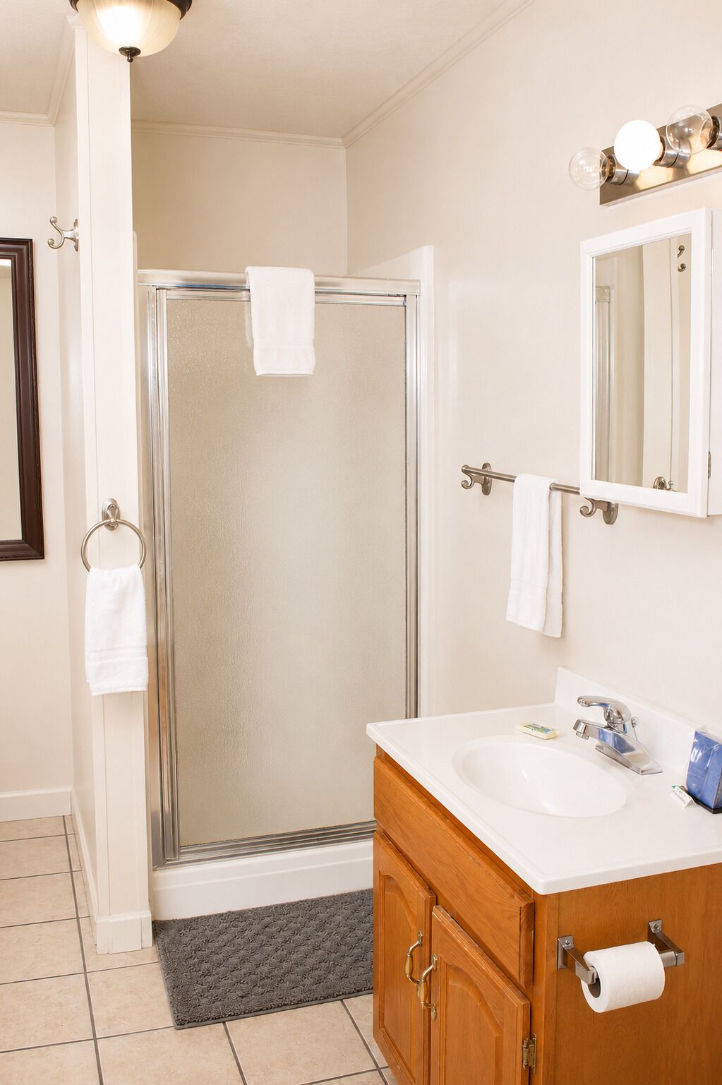 Un bagno con doccia in vetro, lavandino, specchio e portasciugamani.