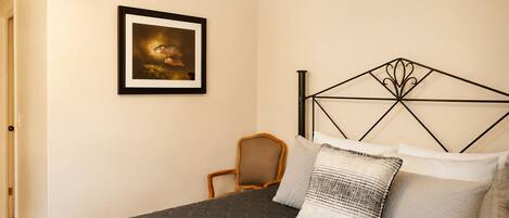A bedroom with a bed, a framed picture on the wall, a chair, and a bed frame with a geometric design.