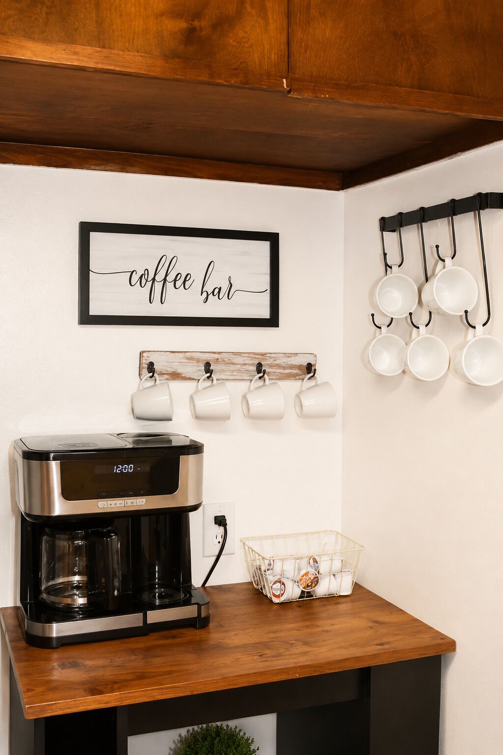 A kitchen with a coffee maker, a coffee bar sign, and a mug rack.
