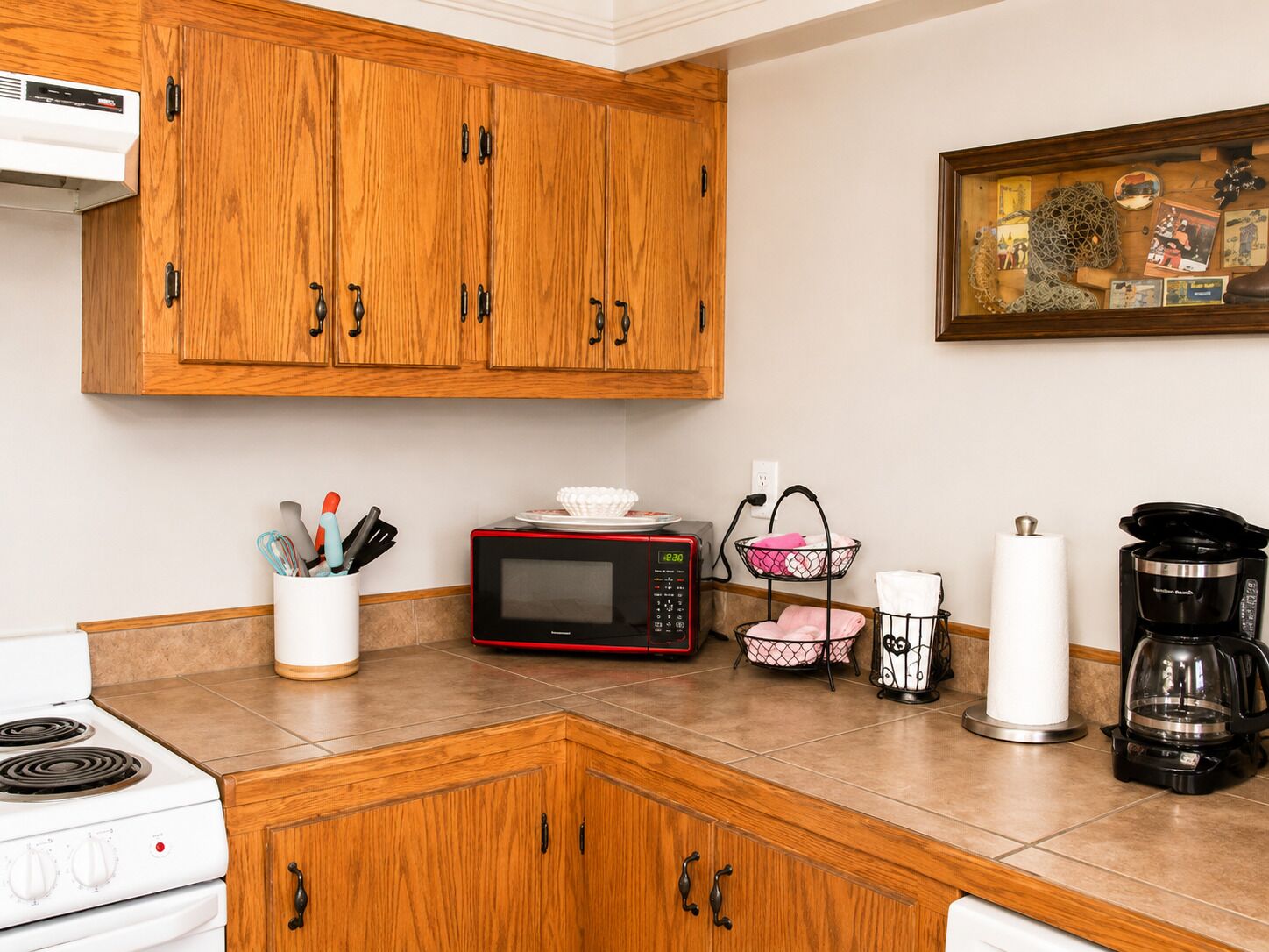 A kitchen with wooden cabinets, a microwave, a coffee maker, and a stove.