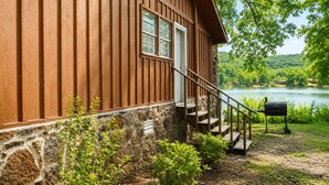 A cabin with a stone foundation, wooden exterior, a staircase, and a view of a lake. - Jack's White River Fishing Resort (Mountain View)