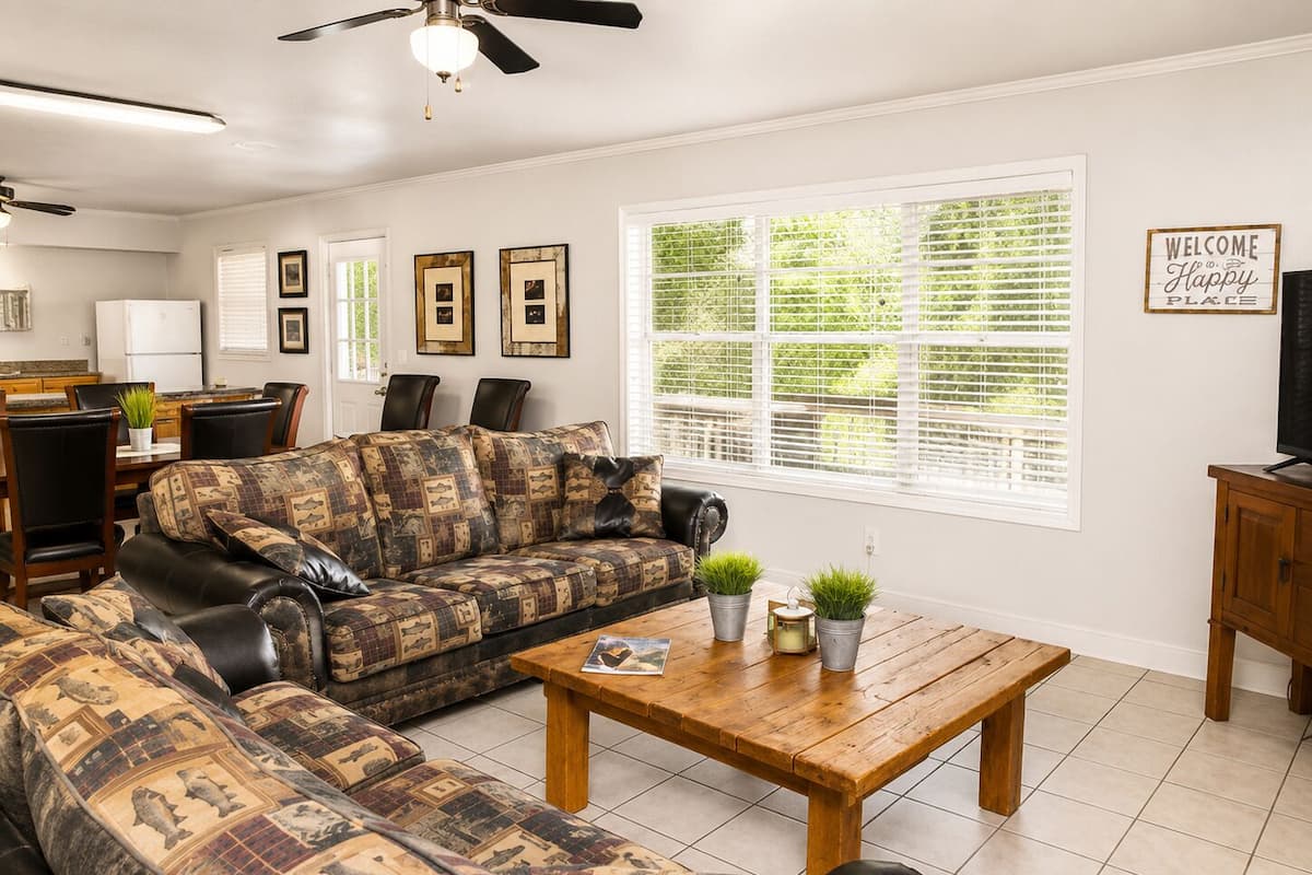 A living room with a patterned sofa, a wooden coffee table, and a television on a wooden cabinet.