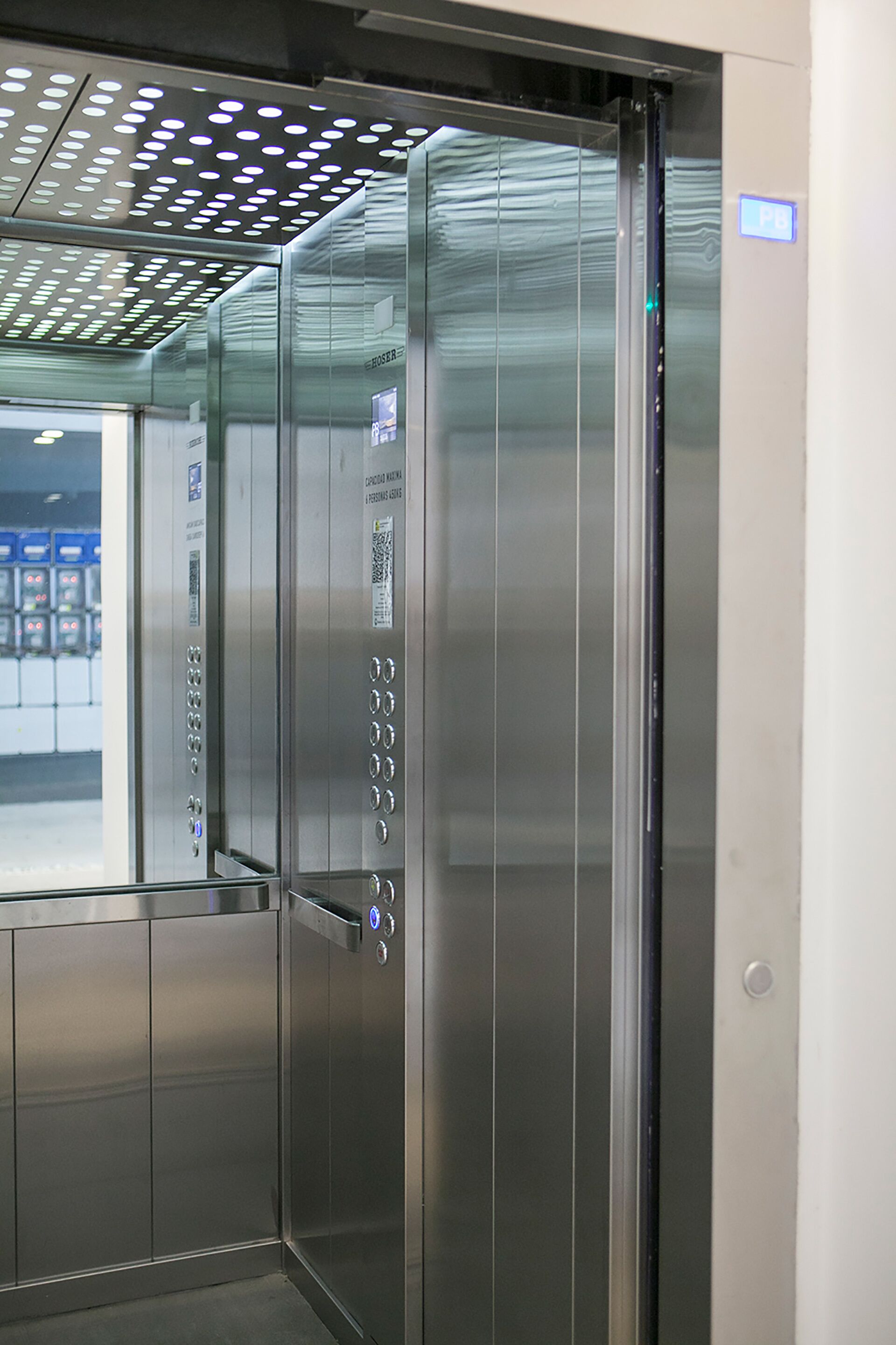 An elevator with metallic walls and a glass panel on the door.