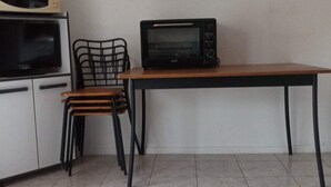 Eine Küchenzeile mit Mikrowelle, Backofen und Stühlen. Ein Gemälde hängt an der Wand.