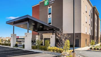 Et Holiday Inn Express hotel med overdækket indgang, parkeringsplads og klar himmel.