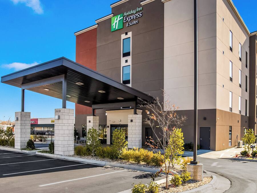 A Holiday Inn Express building with a covered entrance, a parking lot, and a clear sky.