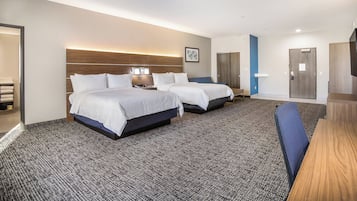A hotel room with two beds, a desk, a chair, a TV, and a bathroom.