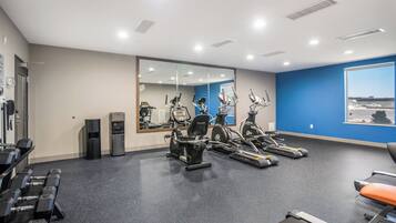Ein Fitnessstudio mit Trainingsgeräten, einem Wasserspender und einem großen Spiegel.
