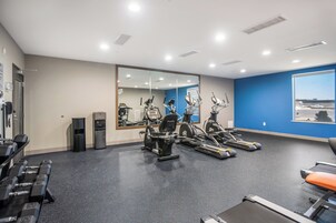 Un gimnasio con equipo de ejercicio, un dispensador de agua y un espejo grande.
