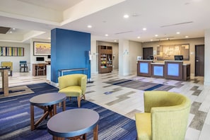 A hotel lobby with a reception desk, seating area, and a children's play area. - Holiday Inn Express & Suites Tulsa East - Catoosa by IHG (Tulsa)