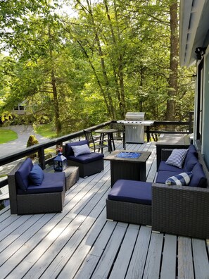 A deck with wicker furniture and a grill.