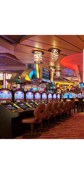 A row of slot machines in a casino with overhead hanging lights.