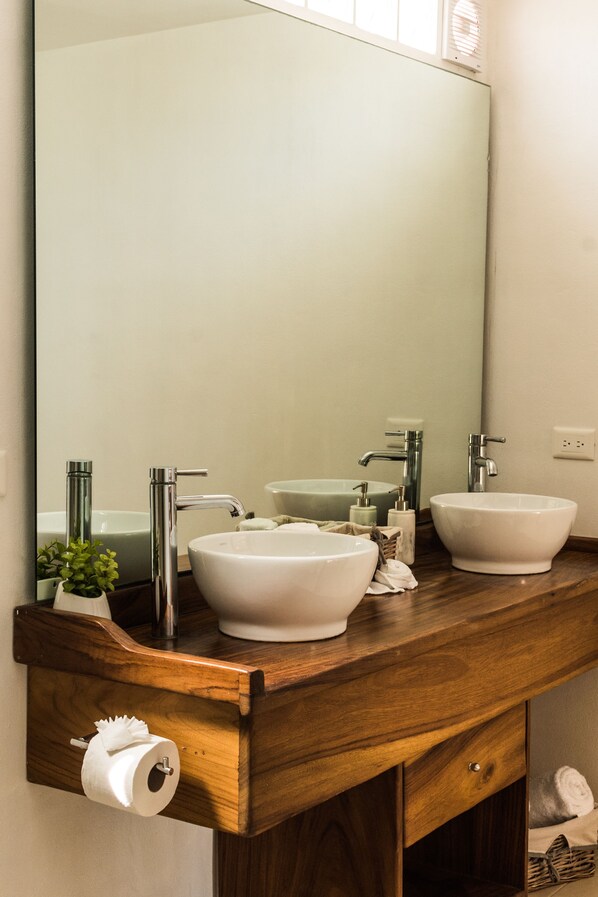 Une salle de bain avec deux lavabos, un miroir et un meuble-lavabo en bois.