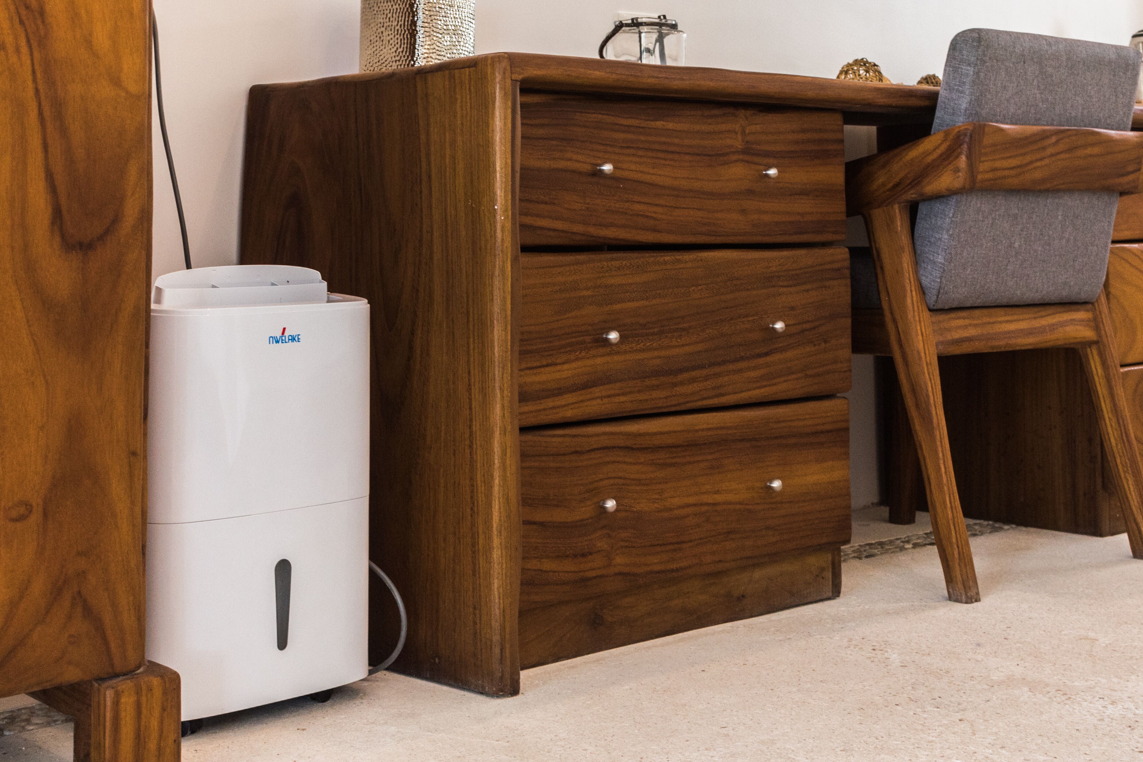 A wooden dresser with drawers and a white appliance, possibly a vacuum cleaner, next to it.