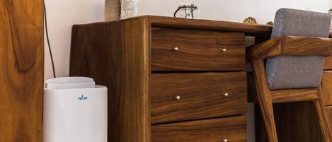 A wooden dresser with drawers and a white appliance, possibly a vacuum cleaner, next to it.