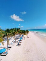 Playa privada, arena blanca, sillas reclinables de playa, sombrillas
