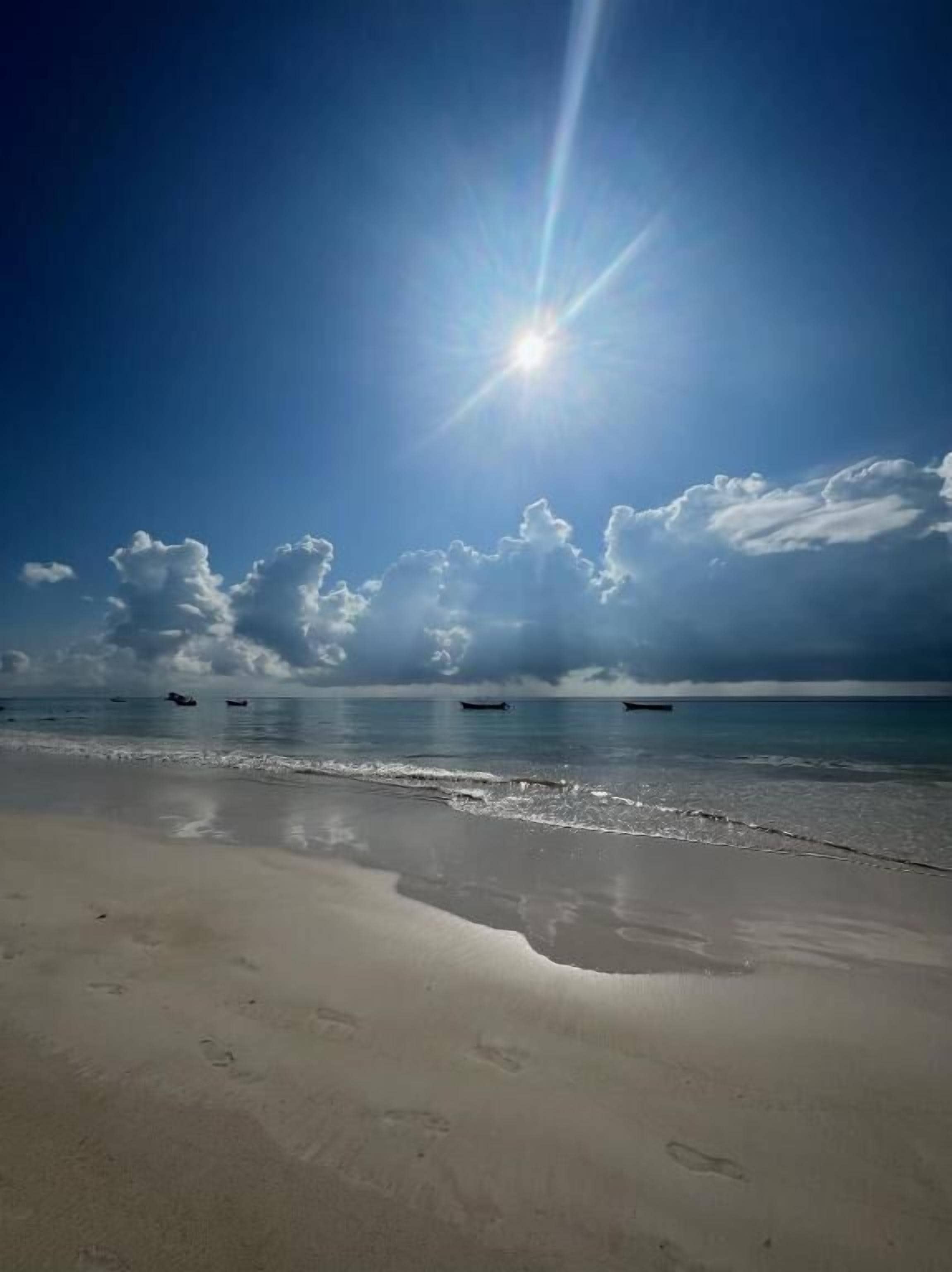 Een strand met een heldere lucht, zonneschijn en een rustige zee.